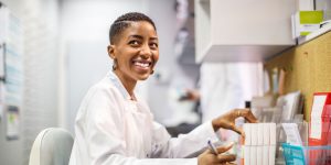 African American pharmacist smiling while filling a prescription