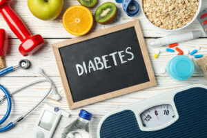 Picture of a chalkboard with the word 'diabetes' on a table with various diabetic measurement tools.