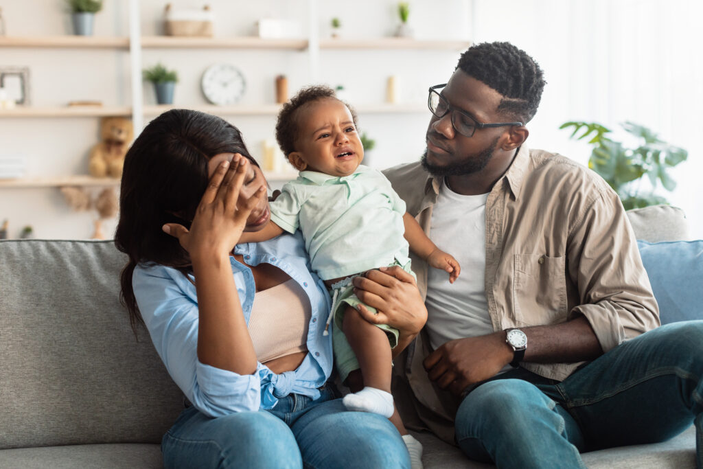 African American parents trying to calm down crying baby.