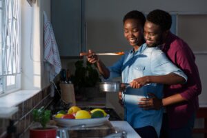 Pregnant couple cooking food in kitchen