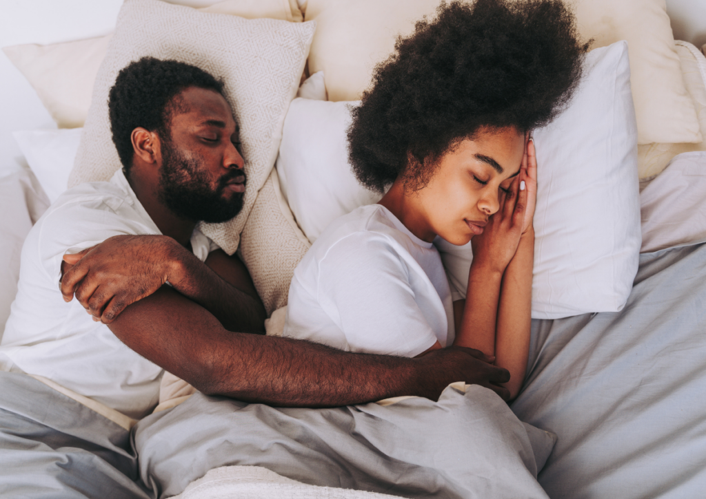 Couple sleeping comfortably in bed.