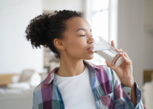 Woman drinking a glass of water to stay hydrated.