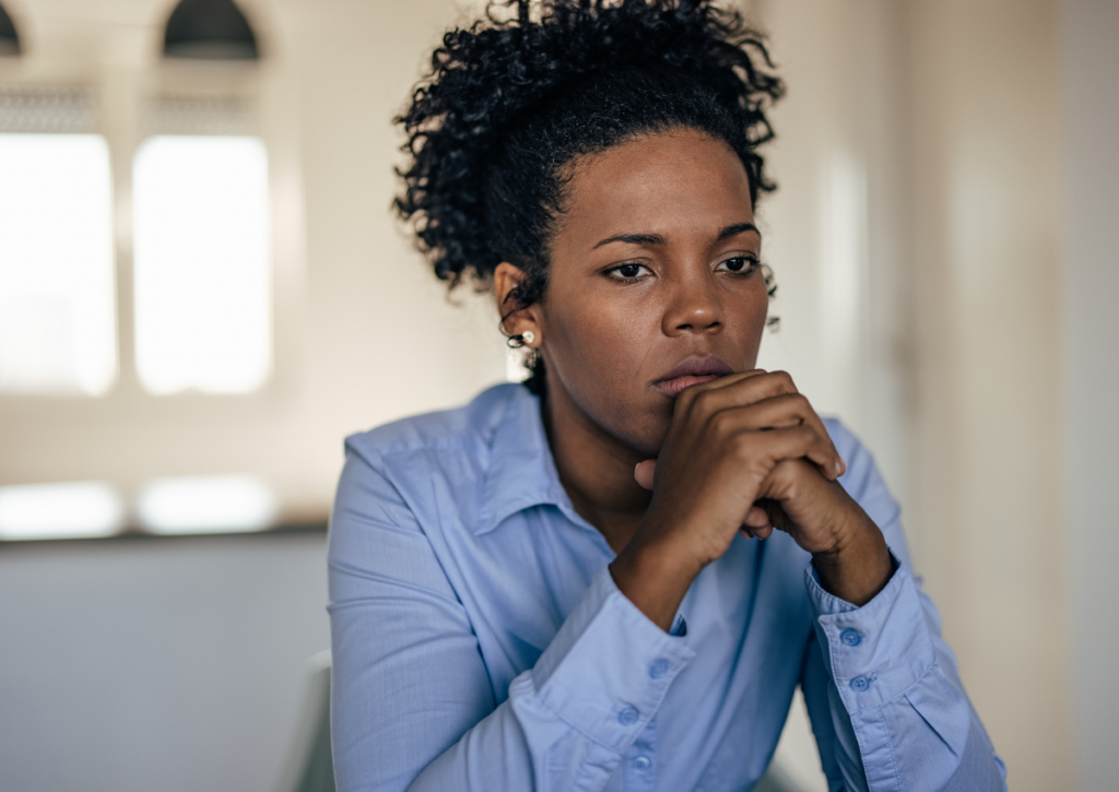 Woman sitting with her hands clasped under her chin.