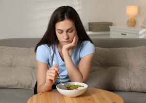 Woman looking discouraged while eating a small meal at home.